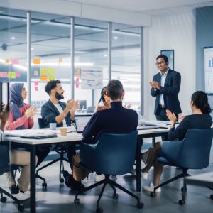 Multi-Ethnic Office Conference Room. Indian CEO does Presentation for Diverse Young Entrepreneurs, Talking, Using TV with Infographics, Statistics, Graphs. Businesspeople Invest in e-Commerce Startup